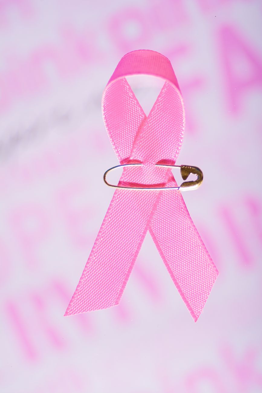 A pink breast cancer awareness ribbon fastened with a safety pin